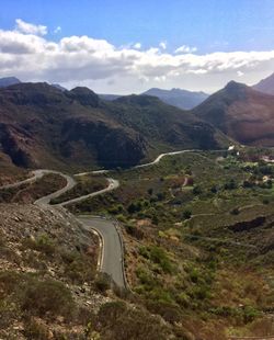 Scenic view of road by mountains against sky