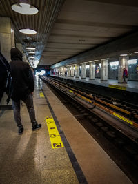Rear view of man standing on railroad station platform