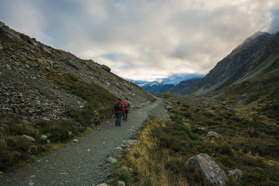 Rear view of people walking on mountain against sky