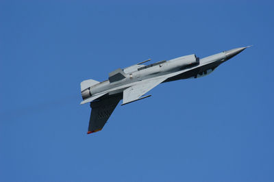 Low angle view of airplane flying against clear blue sky