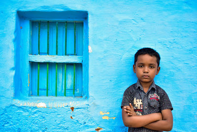 Portrait of cute boy standing against blue wall