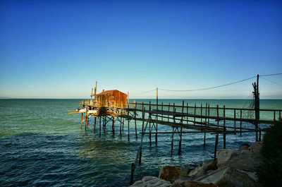 Pier over sea against clear blue sky