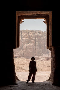 Rear view of woman standing at entrance against mountain