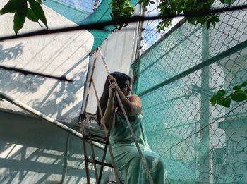 Woman sitting by chainlink fence