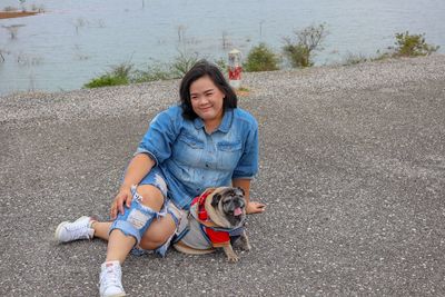 Full length of woman with dog sitting on road