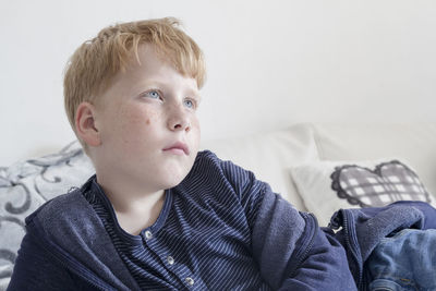 Boy looking up while lying on bed at home