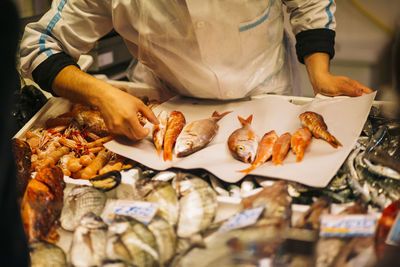 Midsection of man selling fish at market stall