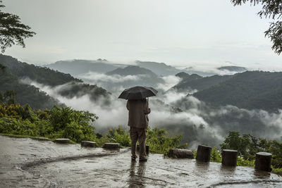 Man standing on snow covered landscape during rainy season