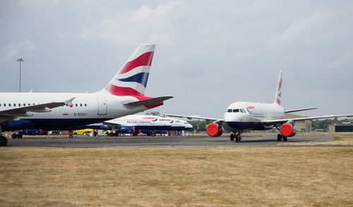 Airplane on airport runway against sky