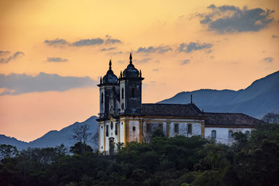 Church by building against sky during sunset