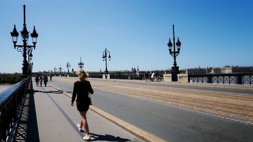 Rear view of woman walking on road against sky