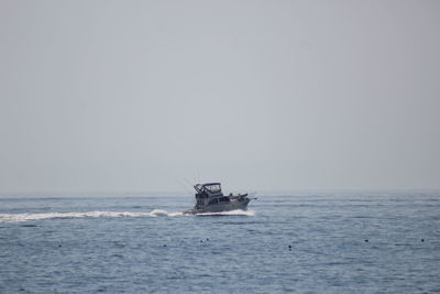 Boat sailing on sea against clear sky