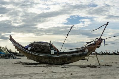 Boat moored on beach against sky