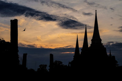 Silhouette of temple against cloudy sky