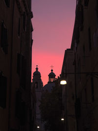 Low angle view of illuminated street light against buildings at sunset