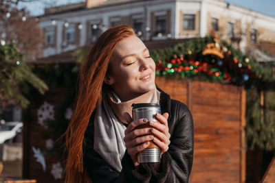 Winter outdoor portrait of a red-haired woman in natural tones. young woman enjoying life on street 