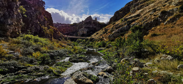 Panoramic view of stream amidst rocks against sky