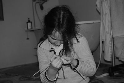 Girl knitting with needles in bathroom