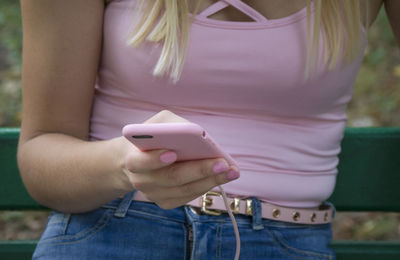 Midsection of woman using mobile phone at park