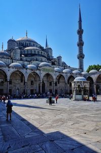 People at temple against clear blue sky