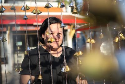 Portrait of woman seen through bells hanging at market