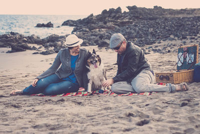 Couple with dog sitting on shore at beach