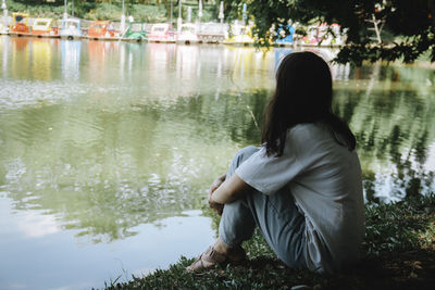 Side view of teenage girl sitting by lake