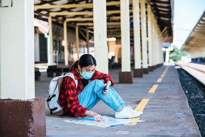 Woman sitting on footpath in city