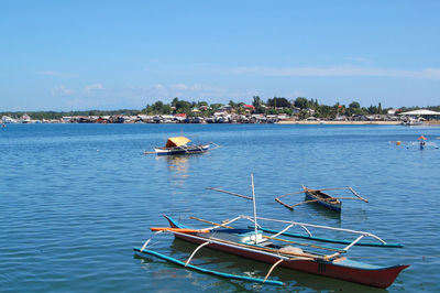 Boat moored in sea against blue sky