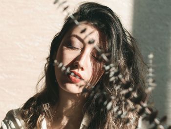 Close-up of beautiful woman by dried plants on sunny day