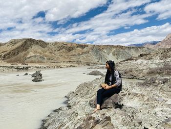 Man sitting on rock against mountains