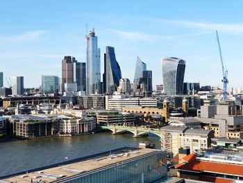 Modern buildings by river against sky in city