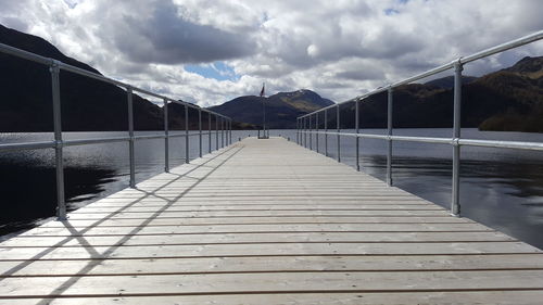 Road leading towards sea against cloudy sky