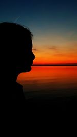 Silhouette woman by sea against sky during sunset