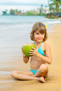 Portrait of girl holding coconut at beach