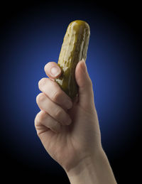 Close-up of hand holding ice cream against black background