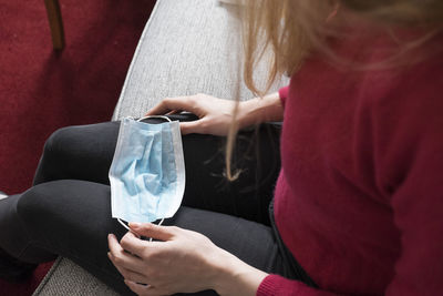 Midsection of woman holding while sitting outdoors