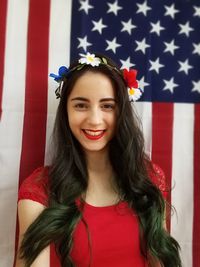 Portrait of beautiful young woman with long black hair against american flag