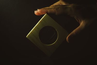 Human hand holding coffee cup against black background
