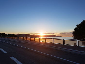 View of road against clear sky at sunset