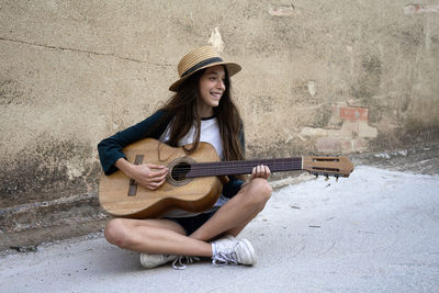 Full length of young woman playing guitar