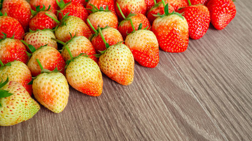 Top view photo, a heap of fresh berry fruit, red strawberry on wooden background with coppy space