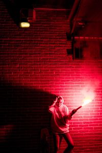 Full length of man standing against illuminated wall