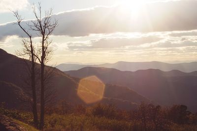 Sun shining through clouds over mountains