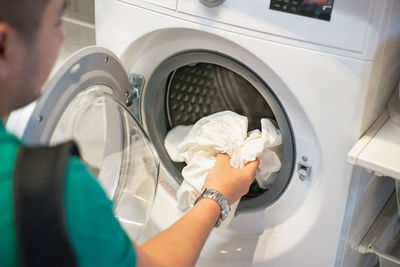 High angle view of man putting laundry in washing machine