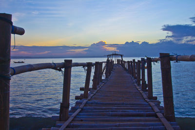 Pier over sea against sky during sunset