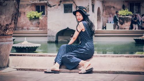 Full length portrait of young woman sitting outdoors