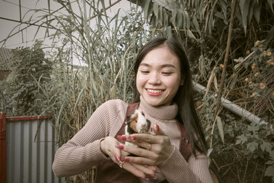 Portrait of young woman standing against plants