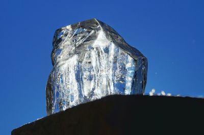 Close-up of ice crystal against clear blue sky