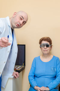 A male optometrist checks the eyesight of an adult woman with a trial frame